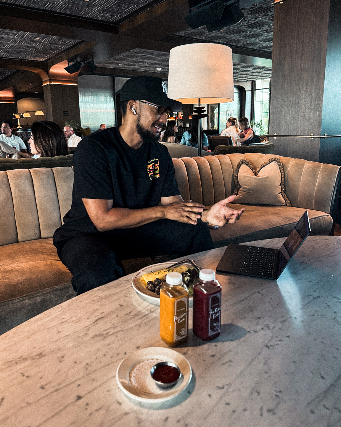 Laughing through a conversation in an upscale lounge, laptop open over brunch